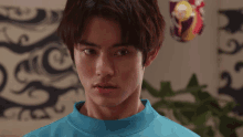a young man in a blue shirt is making a funny face and looking at the camera .