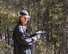 a man is holding a gun in the woods and smiling .
