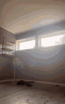 a room with a fan and a window with the sun shining through it
