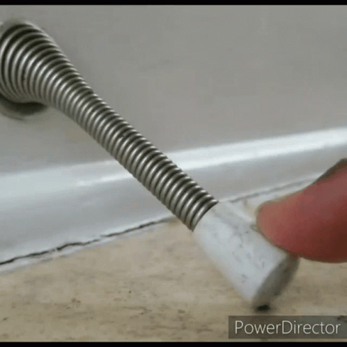 a person 's finger is pressing a door stop on a floor