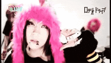 a woman wearing a pink wig and a cat ear hat is standing in front of a group of people .