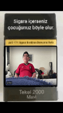 a boy in a red shirt sits on a bed in front of a sign that says tekel 2000