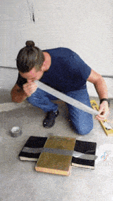 a man in a blue shirt is kneeling on the floor with duct tape and a book that says ' architectural '