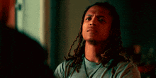 a man with dreadlocks and a grey shirt is talking to another man