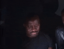 a man in a black shirt is sitting in the dark with his eyes closed