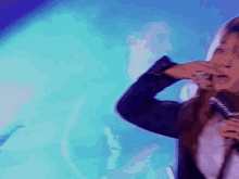 a woman singing into a microphone with a blue background behind her