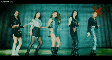 a group of women are standing next to each other and dancing in front of a fence .