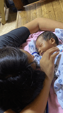 a woman is holding a baby who is wearing a blue anchor outfit