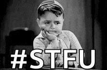 a black and white photo of a little boy sitting at a desk with his hand on his chin and the words `` # stfu '' .