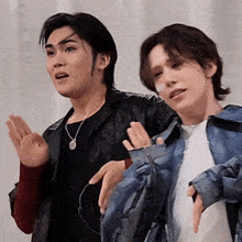 two men are standing next to each other with their hands up