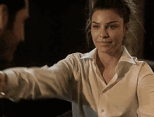 a woman in a white shirt is reaching out her arm towards a man