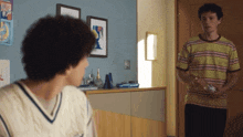 a man in a striped shirt is standing next to another man in a room