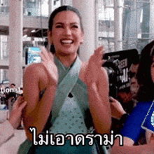 a woman in a blue dress is clapping her hands and smiling