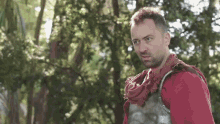 a man in armor is standing in the middle of a forest .