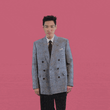 a man wearing a suit and tie is making a heart shape with his hands