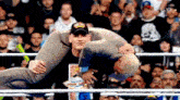 a man is carrying another man in a wrestling ring while a crowd watches .