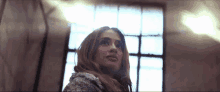 a woman with long hair looks out a window