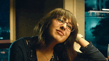 a woman wearing glasses and a watch has her hand on her forehead