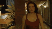a woman in a tank top stands in a hallway