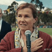 a woman stands in front of a microphone with a netflix logo on the bottom