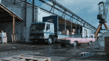 a pink car is driving past a truck that says t10 on it
