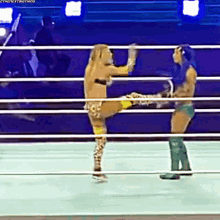 two women are wrestling in a ring and one of them is kicking the other .
