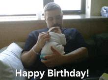 a man is holding a baby in his arms with the words happy birthday written on the bottom .