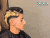a man with a mohawk is getting his hair dyed