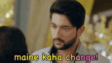 a man with a beard is looking at a woman with the words maine kaha change written above him .