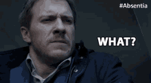 a man with a beard says what in front of a #absentia logo