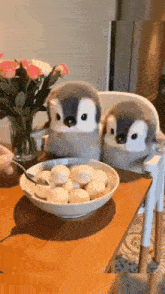 two stuffed penguins are sitting in a high chair next to a bowl of cereal .