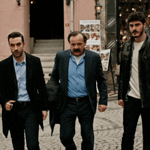three men are walking down a cobblestone street in front of a sign that says " istanbul "