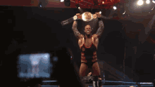 a wrestler holding a canadian heavyweight championship belt over his head