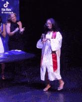 a girl in a graduation cap and gown is dancing on stage
