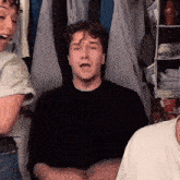 a man in a black shirt is making a funny face in front of a closet