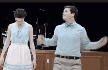a man and a woman are dancing on a stage . the man is wearing a bow tie .