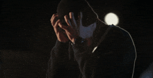 a man in a hood covering his face with his hands