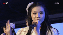 a woman singing into a microphone with the word live on the bottom right