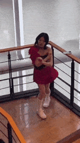 a woman in a red dress is dancing on a wooden floor in a room .