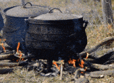 two pots are cooking over a fire in a field