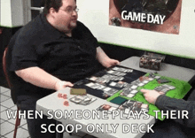 a fat man is sitting at a table playing a board game with another man .