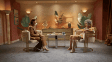 two women sit in chairs in a living room
