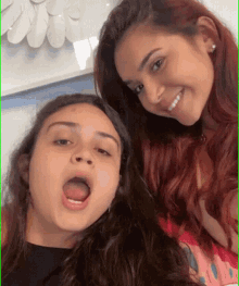 two girls are posing for a picture with their mouths open and smiling .