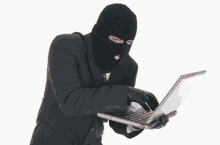 a man in a black suit and black gloves holds a laptop