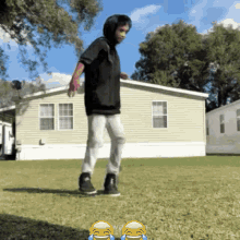 a young boy is standing in front of a mobile home with two laughing faces on the grass