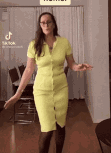 a woman in a yellow dress and black tights is dancing in a living room .