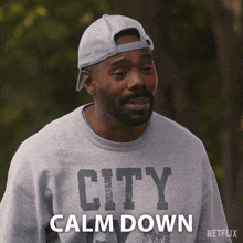 a man wearing a hat and a city sweatshirt says calm down