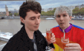 two men toasting with champagne glasses in front of a body of water