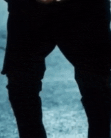 a young boy in a suit and tie is kneeling down on the ground holding a red apple .