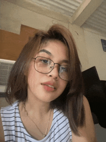 a woman wearing glasses and a striped shirt is looking at the camera